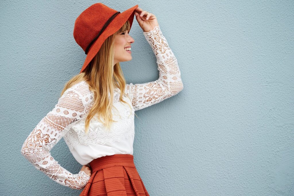 On the Change Delivery Partner page, this is a young woman wearing a stylish red hat and a white lace top, smiling and posing against a light blue wall. She looks relaxed and confident, exuding a sense of modern fashion and individuality.